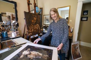 Rachel Thompson/News-Register##In her home studio, McMinnville artist Kim Palacios shows some of her depictions of Christian images as well as landscapes. She started the painting of Jesus holding an infant, which is on the easel, during Easter services at her church. After capturing the basic image while the congregation watched, she brought the painting home to add color and details.