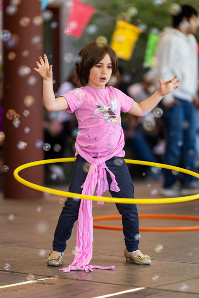 Rachel Thompson/News-Register##Five-year-old Emilia McEachern spins a hula hoop 
as bubbles drift through the library breezeway.