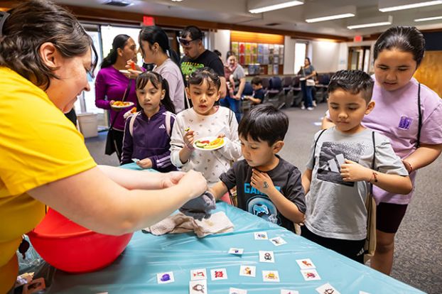 Rachel Thompson/News-Register##Santi Serrato, 5, gets a temporary tattoo from Children&rsquo;s Librarian Jackie Quiroz during D&iacute;a de los Ni&ntilde;os on Saturday, April 25, at the McMinnville Public Library, as Elizabeth Serrato, 8, and Angela Serrato, 8, watch at left, and Axel Morales, 7, and Ayleen Morales, 9, wait their turn at right.