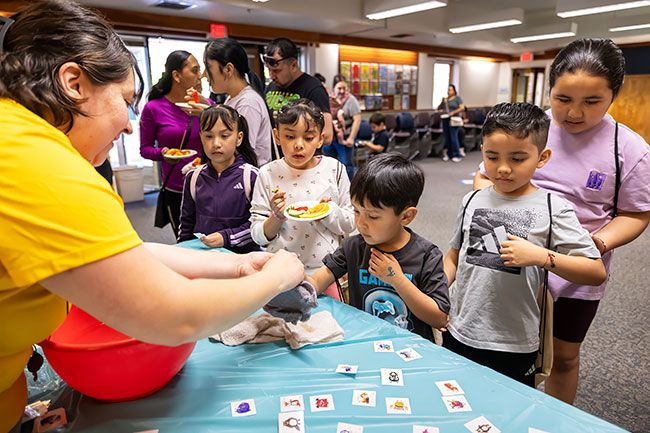 Rachel Thompson/News-Register##Santi Serrato, 5, gets a temporary tattoo from Children&rsquo;s Librarian Jackie Quiroz during D&iacute;a de los Ni&ntilde;os on Saturday, April 25, at the McMinnville Public Library, as Elizabeth Serrato, 8, and Angela Serrato, 8, watch at left, and Axel Morales, 7, and Ayleen Morales, 9, wait their turn at right.