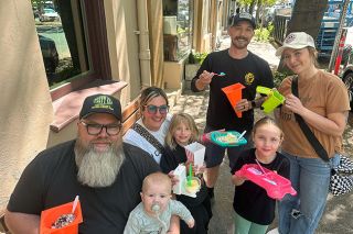 Kirby Neumann-Rea/News-Register##McMinnville residents enjoy ice cream from unusual containers, including traffic cones and a toy toilet bowl. Sitting are Andrew Gates and his wife, Tiffany, holding their children Finlee and Harper. Standing are McKenzie and Cecil Gephart with their daughter Kennedy.