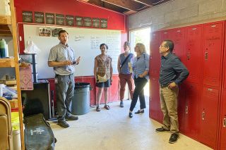 Starla Pointer/News-Register##Inside the existing junior-varsity softball team room, Brian Crain, left, director of facilities for the school district, talks about needed improvements during a tour of athletic facilities in 2025. Construction of a new, more spacious team room will start this spring. On the tour, Crain was accompanied by, from center, school board members LuAnn Anderson and Christine Bader, Superintendent Kourtney Ferrua and board member Gerardo Partida.