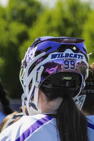 Photo courtesy of Amelia Solt##Senior Tenley Hodge (99) standing in the pregame huddle, sporting a metallic purple goalie helmet.