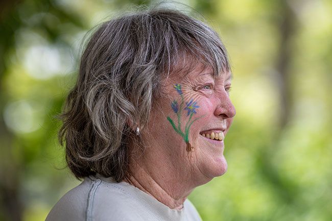 Rachel Thompson/News-Register##Patricia Farrell of the Native Plant Society of Oregon smiles while speaking with visitors outside Nicholson Library, a camas flower painted on her cheek by a Linfield student.
Message Racheal Winter