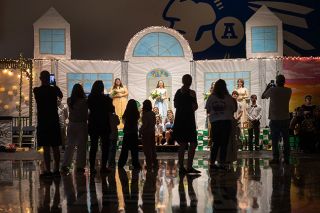 Rachel Thompson/ the News-Register##Silhouetted against stage lights, family members and friends gather on the gym floor to photograph the May Day court during Amity High School&rsquo;s 101st annual May Day celebration on Friday, May 1. The long-running tradition featured a maypole dance, student performances, the crowning of the court and a senior waltz celebrating the Class of 2026.