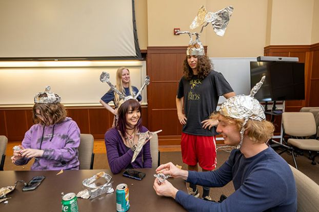 Rachel Thompson/News-Register##From left, Linfield students Ash Richards, Helen Yang, Jacob MacFarland and Soren Gauger create and model handmade tinfoil hats while organizer Megan Moonfall, background center, looks on during Foiled Again!, a UFO-themed gathering Wednesday at T.J. Day Hall on the Linfield University campus. Hosted by MacApps LLC ahead of McMinnville&rsquo;s annual UFO Festival, the event grew out of smaller hat-making parties previously held at the Moonfalls&rsquo; home