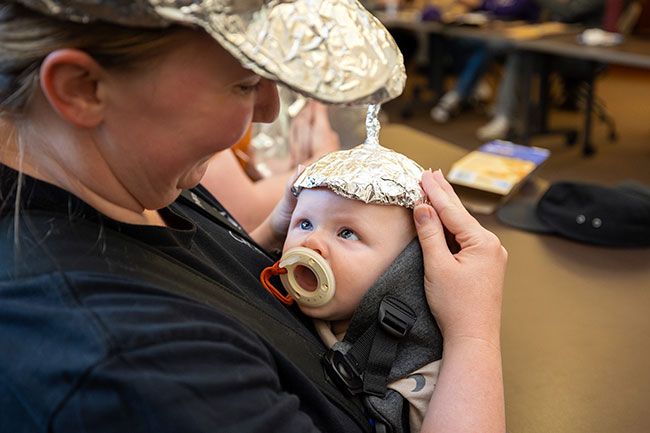 Rachel Thompson/News-Register##Audrey Dawson of McMinnville adjusts a tiny foil hat on her 3-month-old, Cyrus.