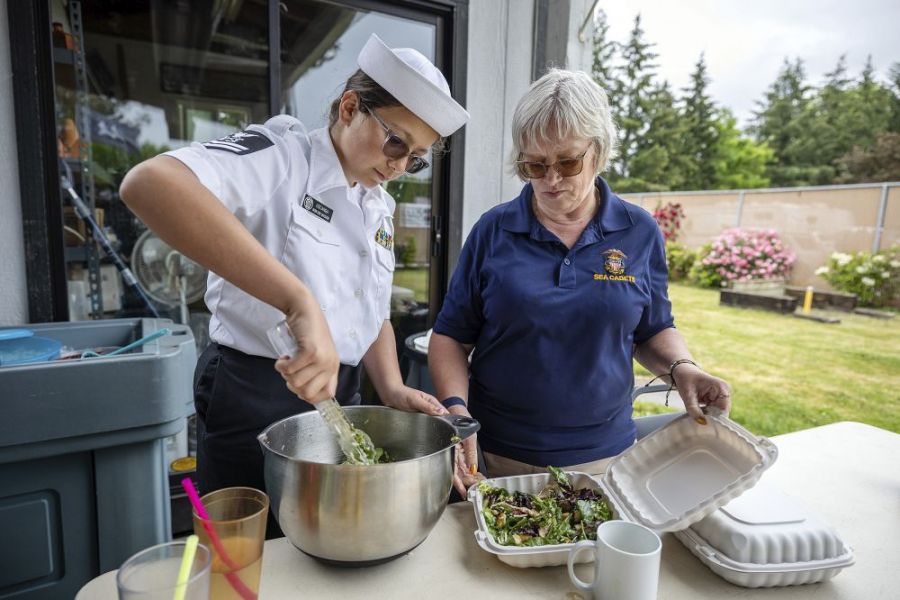 Rachel Thompson/News-Register##Ayla Uscanga, 12, left, portions salad into takeout containers, working alongside Lori Qualls during the American Legion Memorial Day barbecue.