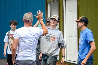 Emily Bonsant/News-Register##Everyone Village Executive Director Gabe Piechowicz high-fives Joshua Taylor, who did plumbing and electrical work on the mobile bathroom and laundry unit along with Kody Remington, right. Amity High School trade students have built several mobile housing units for the Eugene-based transitional shelter program for those experiencing homelessness.