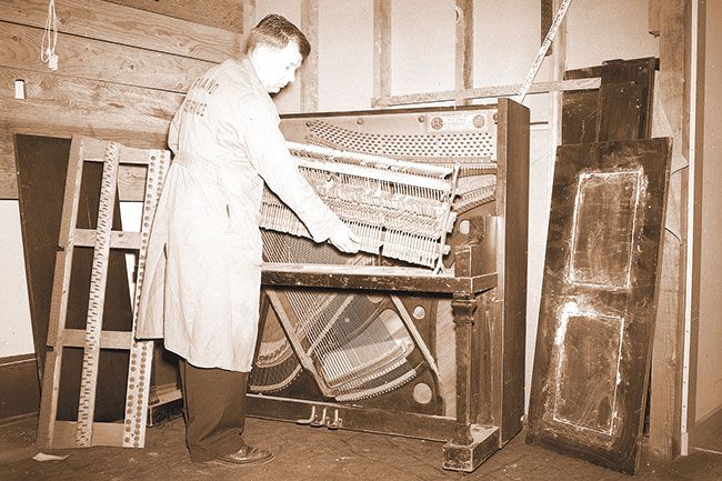##(June 5, 1956) This old piano soon will be a modern instrument after remodeling at the Severson Music company, 337 N. Davis Street. Selmer Severson, who opened the store recently, dismantles the piano in preparation to the remodeling and reconditioning. The new McMinnville business will handle new and used pianos and other musical instruments. Future plans call for music instructions and a record and sheet music department. Severson has served as piano tuner here for nearly ten years and is a former music teacher.