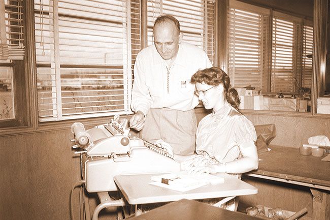 ##(June 4, 1956) A new machine for computing payrolls of pickers at the Alderman Farms is explained to Donna Conn by Jesse Payne, office manager at Alderman&rsquo;s. The machine, described as five adding machines in one, will be used in conjunction with an automatic check writer which enters amount, date and signature on a check in one operation and gives totals on the entire payroll. Many hand processes will be eliminated by use of the machine.