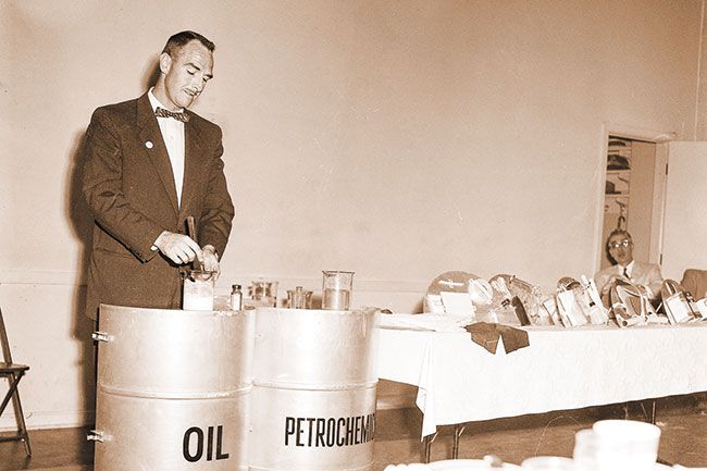 ##(June 5, 1956) Glen Darroch, Portland Associated Oil Co. employee and McMinnville Chamber of Commerce speaker Monday, makes balls of rubber from petrochemicals as part of a forum luncheon program portraying products from the &ldquo;magic barrel&rdquo; that we gain from oil. He displayed dozens of products now vital parts of American life which come from the petrochemical industry and forecast a multitude of changes in our future living through products from petroleum.