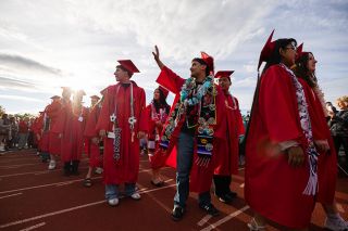 Rachel Thompson/News-Register##Angel Orosco Huerta pauses to acknowledge family and friends in the stands while lining up with classmates before McMinnville High School&rsquo;s commencement Friday evening at Wortman Stadium. 547 members of the Class of 2026 received diplomas during the school&rsquo;s 116th graduation ceremony.