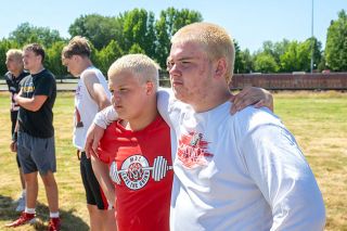 Rusty Rae/News-Register##Incoming McMinnville juniors Sunny and Kaven Johnson lean on each other for a short rest during a Grizzly practice session at the Linfield football camp on Friday, June 19.