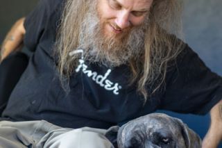 Rachel Thompson/News-Register##Franny, a Cane Corso, cuddles with Johnny Wheels at his Willamina home. The musician cherishes time spent with Franny and his pit bull, Zeppelin, just as he relishes time on stage playing the blues, writing music and performing.