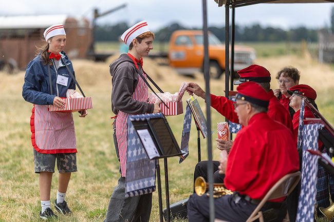 Rachel Thompson/News-Register##Volunteers Micah Bruckner, center, and Isla Hizzey, left, serve popcorn to members of the Whiskey Flats Brass Band on Saturday, June 27. Performing on instruments dating to 1871, the Stevenson, Washington-based band played period music between innings as well as a pre-game concert. This was the ensemble&rsquo;s third time playing during the Yamhill County History Museum&rsquo;s annual Vintage Base Ball game.