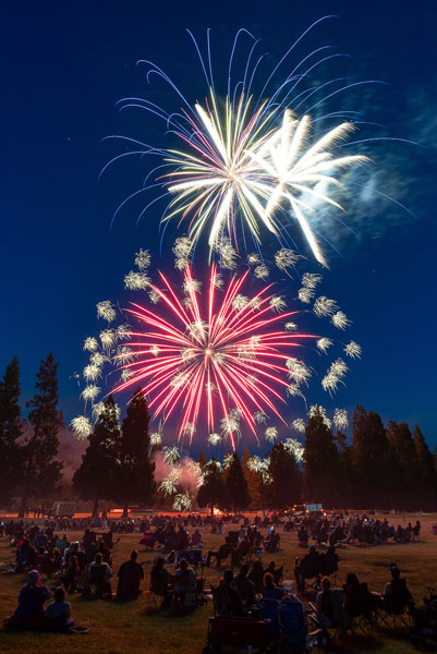 Rachel Thompson/News-Register##Fireworks illuminate the Dayton sky over spectators gathered in the field behind the post office for the third annual Stars and Stripes Community Firework Show Friday evening