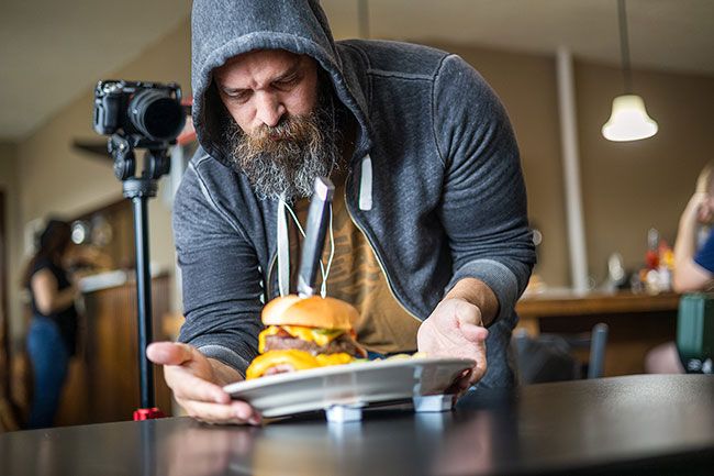 Rachel Thompson/News-Register##Show videographer Adam Rodriguez props up the Coyote Burger on jelly packets to capture close-up footage during filming at the Willamina restaurant. The burger features two half-pound beef patties topped with bacon, ham, egg, cheese, lettuce, tomato, onion, pickle and mayonnaise on a grilled bun.