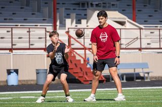 Nathan Ecker/News-Register##Dayton Head Coach Kiegan Schaan (right) stands in as an obstacle for wide receivers like incoming freshman Ethan Christensen (left) to work around during route running drills at a summer practice session.