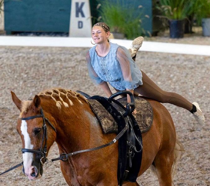 Photo courtesy of EVUSA##Sarah-Anne House twirls around the back of her steed during an equine vaulting training camp. In the sport, traditional saddles are replaced with a special surcingle with handles, which aid the vaulter in performing certain moves. For competitions, House often rides borrowed horses, creating a loving relationship with each one.