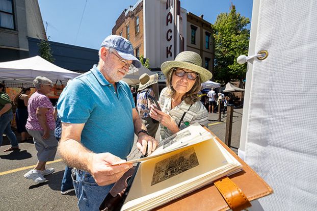 Rachel Thompson/News-Register##During the inaugural McMinnville Art Festival on Saturday, Michael and Michele George of Salem browse a portfolio of prints by Hillsboro artist Egor Shokoladov. The Belarusian-born artist specializes in intricate surrealist and symbolic copper-plate etchings.