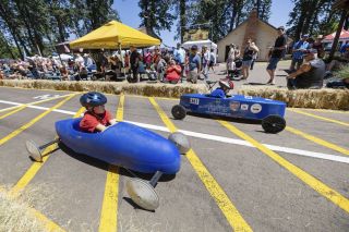 Rachel Thompson/News-Register##Best friends Ben Blatner, foreground, and Jaxon Alexander speed across the finish line during the annual soap box derby Saturday at Yamhill Derby Days in Beulah Park. The annual race remains the centerpiece of the longtime community festival.