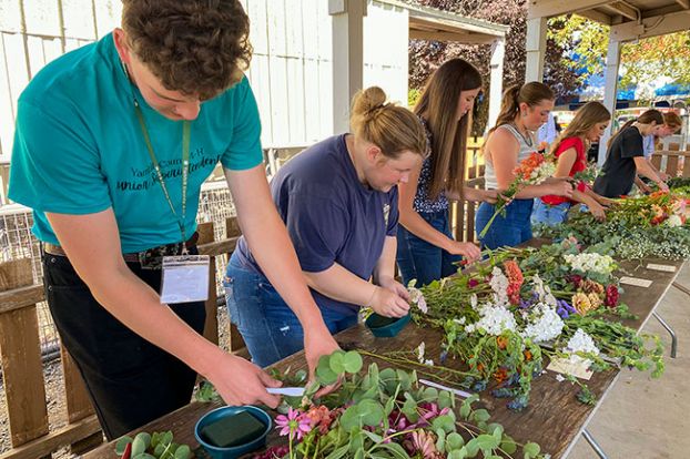 Starla Pointer/News-Register##William Webber, left, and other senior 4-H members start arranging greenery and flowers in a competition Monday at the Yamhill County Fair & Rodeo. About 80 young people competed in several age-group categories of the floral contest. Their arrangements are on display in the horticulture area at the fair, which runs today through Saturday on the fairgrounds in McMinnville. It features nightly concerts and rodeo shows, Saturday&rsquo;s demolition derby and numerous displays and animal contests.