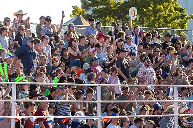 Rachel Thompson/News-Register##Spectators cheer from packed grandstands Saturday as the Summertime Smash demolition derby unfolds. Fans express their excitement with raucous applause, slapping inflatable thunder sticks and waves of their hats.