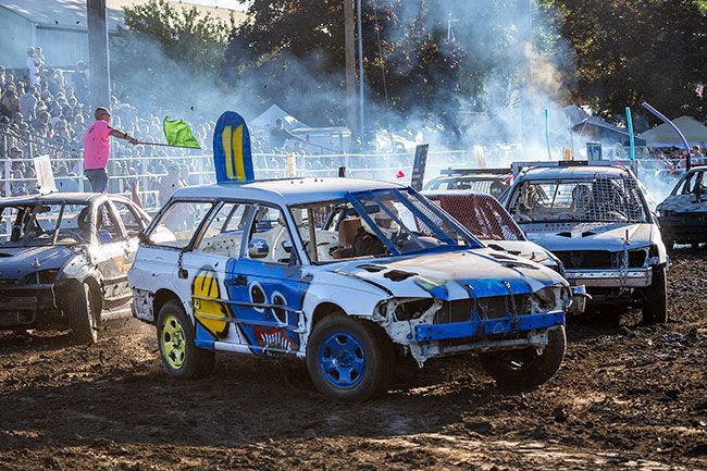 Rachel Thompson/News-Register##Engines roar to life in the Cascade Arena as head flagger Roger Young Jr. sweeps the green flag through the air to begin sedan lap competition.