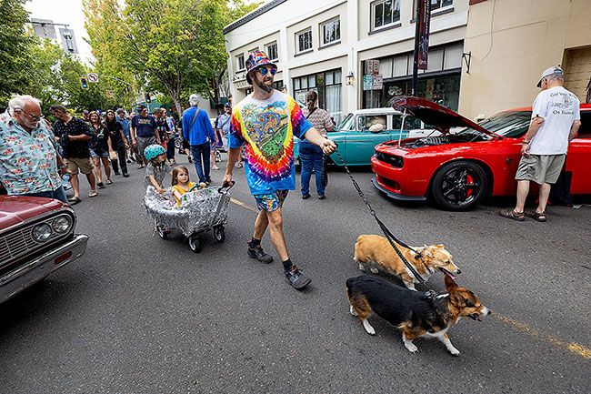 Rachel Thompson/The News-Register##Troy Chambers of McMinnville guides a family caravan through the Cruising McMinnville car show Saturday, pulling daughter Stella, 4, in a tinsel-trimmed wagon as her sister, Dylan, 6, hitches a ride behind on roller skates. Corgis Chef and Cheddar lead the way east along Third between Ford and Galloway streets.