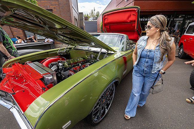 Rachel Thompson/The News-Register##Elisa Torres of Guadalajara, Mexico, checks out a customized 1968 Oldsmobile 442 convertible as Earth, Wind & Fire provides the soundtrack from the rear of the car.