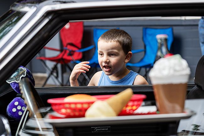 Rachel Thompson/The News-Register##Zeppelin Brown, 4, of Sheridan calls his grandfather, Greg Brown, over for a closer look at a 1969 Chevrolet Camaro and its window-mounted drive-in tray. &ldquo;He&rsquo;s all excited to see his Hot Wheels in full size,&rdquo; his grandfather said.