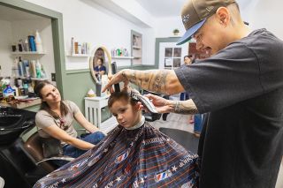 Rachel Thompson/News-Register##Marni Cochran watches as barber Gerardo Ramirez gives a free haircut to her 4-year-old, Maverick, who will be starting 
pre-kindergarten Monday at Newby Elementary School.