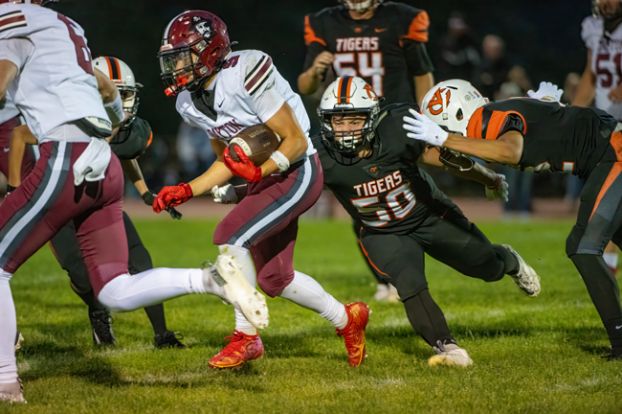 Rusty Rae/News-Register##Dayton junior John Corona avoids the ire of YC junior Gabe Pond and other Tiger defenders on a rushing attempt in the Pirates 35-0 victory at YC on Friday.