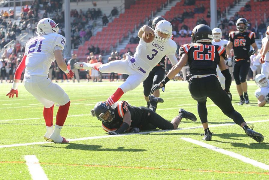 Rockne Roll/News-Register##
Linfield s Aiden Wilder, in his first start as a  Cat quarterback, leaps a Pioneer defender for the first score of the game. Linfield won the game 49-14.
