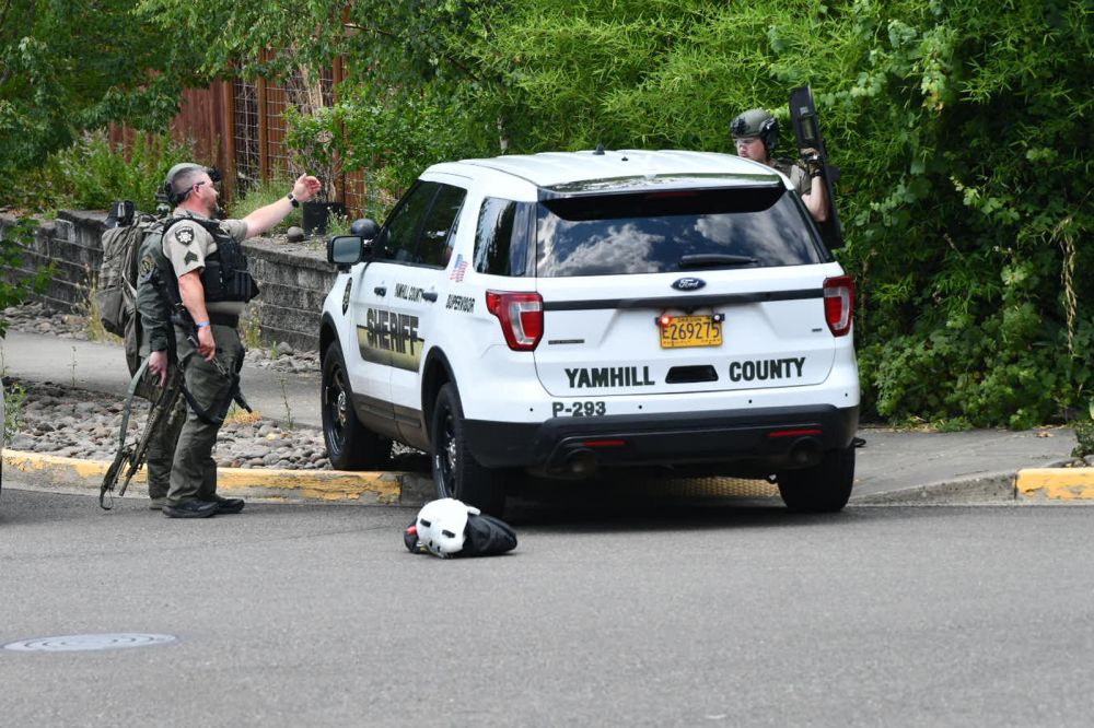 Rusty Rae/News-Register# Ein Mitglied der Sheriff-Abteilung von Yamhill County dirigiert ein anderes Büro in einen sicheren Bereich, während Beamte das Haus in der Mt. Mazama Street umstellten.