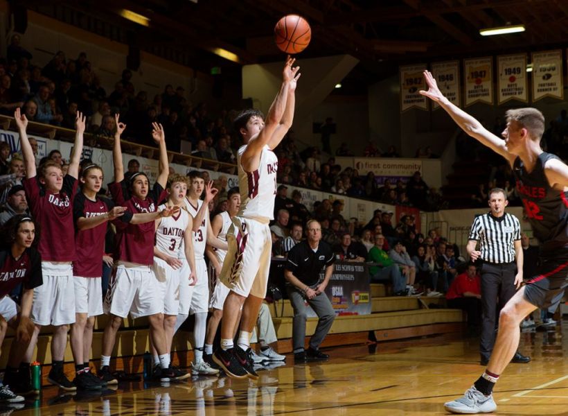 Rockne Roll/News-Register##
Dayton s Braeden Nowlin launches a three as his teammates cheer from the bench.