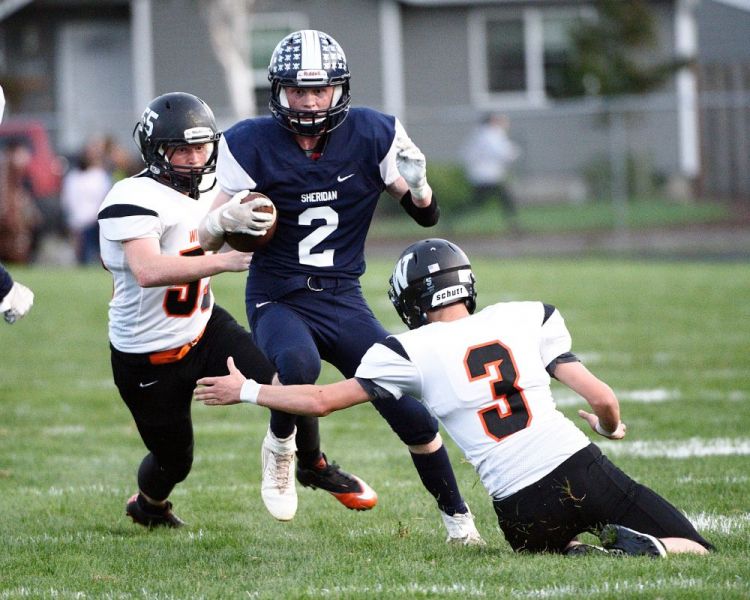 Marcus Larson/News-Register##
Sheridan s Elliott Henley (2) breaks a tackle during a rushing play in tonight s rivalry game against Willamina. Bulldogs Conrad Farmer (3) and Kyle Anderson (55) attempt to stop Henley.