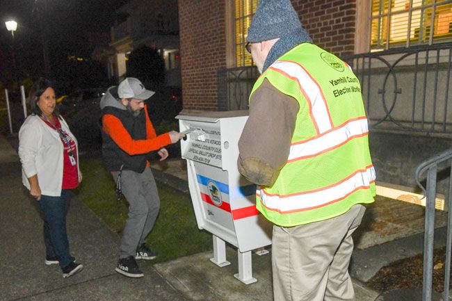 Rusty Rae/News-Register##
As clerk s office workers watch, David Farnsworth, center, slips his ballot into the Yamhill Drop Box outside the county Clerk’s office Tuesday evening.