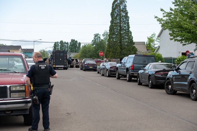 Rusty Rae/News-Register##A McMinnville Police Department K9 officer responds to Monday morning s standoff at a Northwest Evans Street residence in Sheridan as an Oregon State Police SWAT - Special Weapons and Tactical - vehicleis made ready for use.